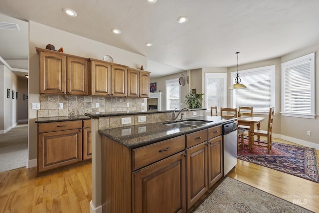 kitchen featuring tasteful backsplash, visible vents, brown cabinetry, dishwasher, and a sink