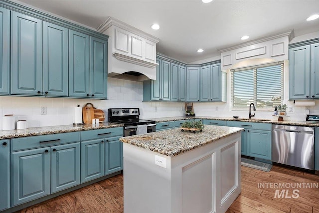 kitchen with blue cabinets, a kitchen island, stainless steel appliances, and wood finished floors