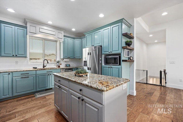 kitchen featuring open shelves, appliances with stainless steel finishes, a kitchen island, and light wood-style floors