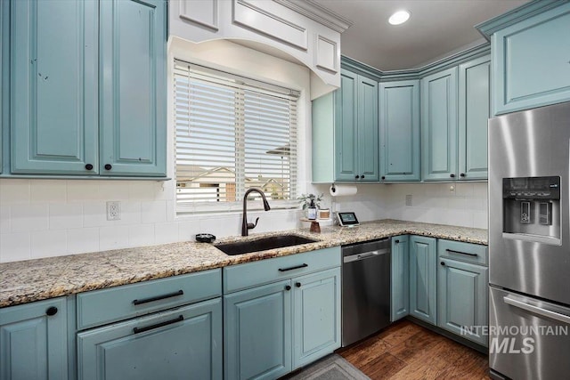 kitchen with dark wood-style flooring, a sink, blue cabinetry, appliances with stainless steel finishes, and decorative backsplash