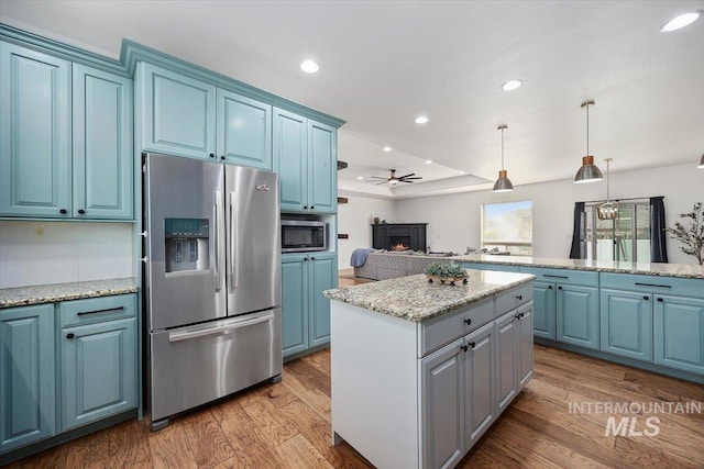 kitchen with blue cabinets, a kitchen island, stainless steel appliances, and decorative light fixtures