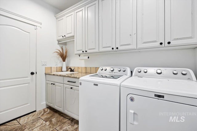 washroom featuring cabinet space, a sink, and washer and clothes dryer