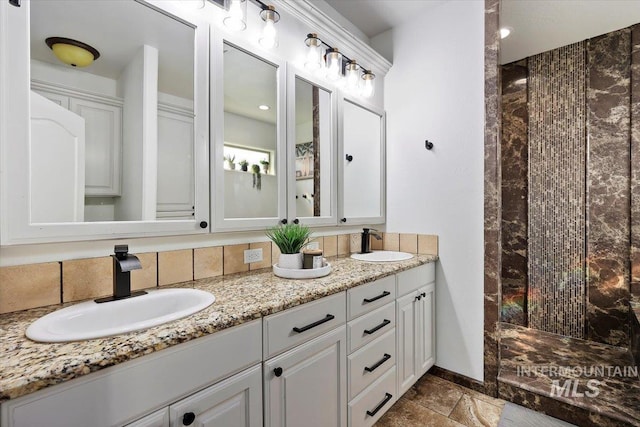 bathroom featuring double vanity, a sink, baseboards, and walk in shower