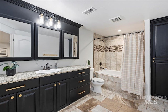 bathroom featuring toilet, tiled shower / bath, visible vents, and vanity