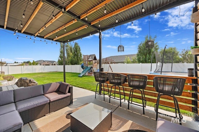 view of patio featuring a playground, a fenced backyard, outdoor lounge area, a bar, and a trampoline