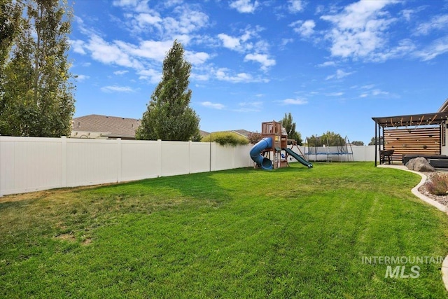 view of yard with a trampoline, a playground, and a fenced backyard