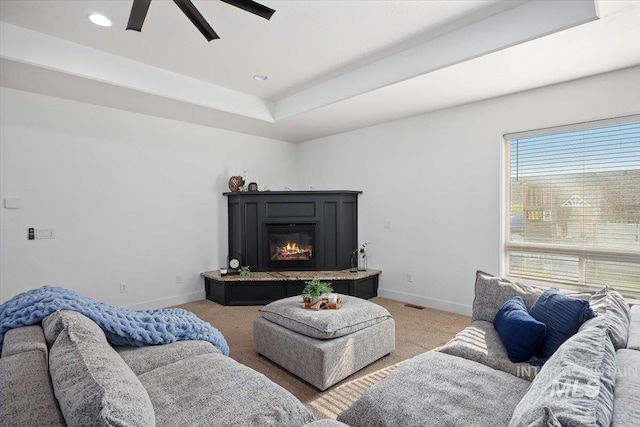 carpeted living area with recessed lighting, visible vents, baseboards, a tray ceiling, and a glass covered fireplace