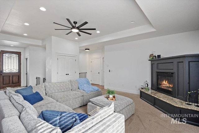 living room featuring recessed lighting, light carpet, a glass covered fireplace, and baseboards