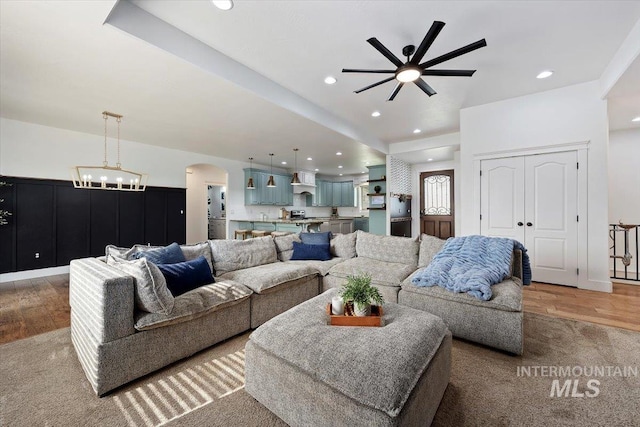 living area with dark wood-type flooring, arched walkways, ceiling fan, and recessed lighting