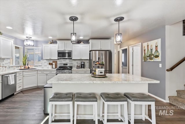 kitchen with white cabinetry, pendant lighting, appliances with stainless steel finishes, and a kitchen island