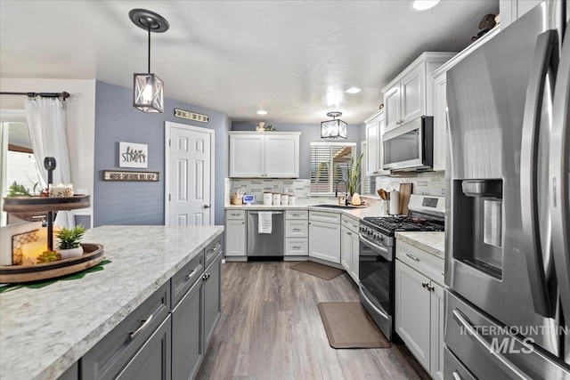 kitchen featuring stainless steel appliances, white cabinets, tasteful backsplash, and sink