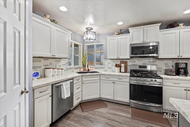 kitchen with decorative backsplash, sink, stainless steel appliances, and white cabinetry