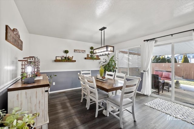 dining room with dark wood-type flooring and a textured ceiling