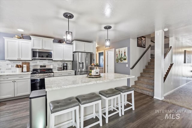 kitchen with white cabinets, hanging light fixtures, and appliances with stainless steel finishes