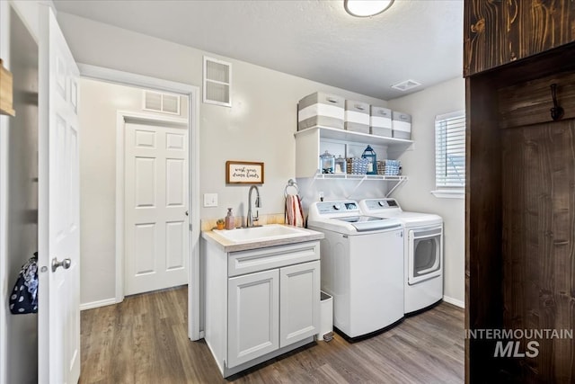 washroom with cabinets, light hardwood / wood-style flooring, washing machine and clothes dryer, and sink