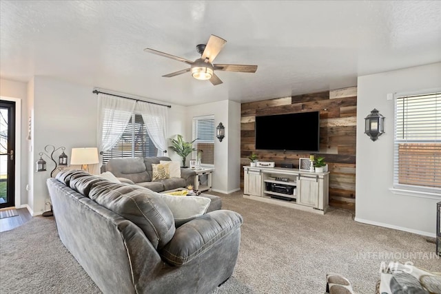 carpeted living room with ceiling fan and wood walls