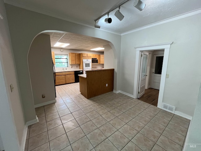 909 E 6th, Moscow, ID 83843 - kitchen featuring arched walkways, black dishwasher, light tile patterned floors, a peninsula, and stainless steel microwave