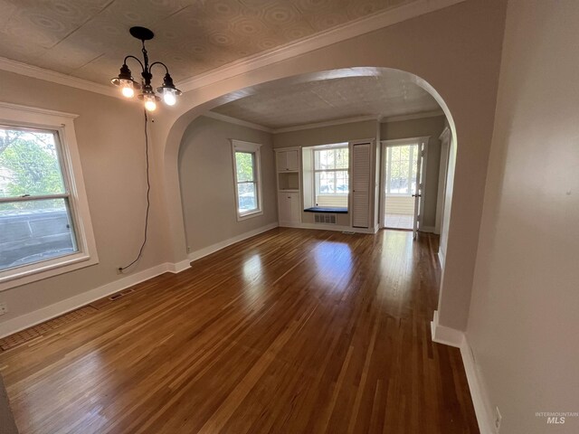 909 E 6th, Moscow, ID 83843 - unfurnished dining area featuring arched walkways, baseboards, dark wood finished floors, a chandelier, and ornamental molding