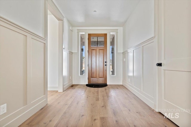 entrance foyer with a wainscoted wall, a decorative wall, and light wood-style flooring