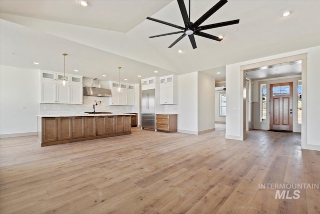 kitchen with open floor plan, white cabinetry, light wood finished floors, and decorative backsplash