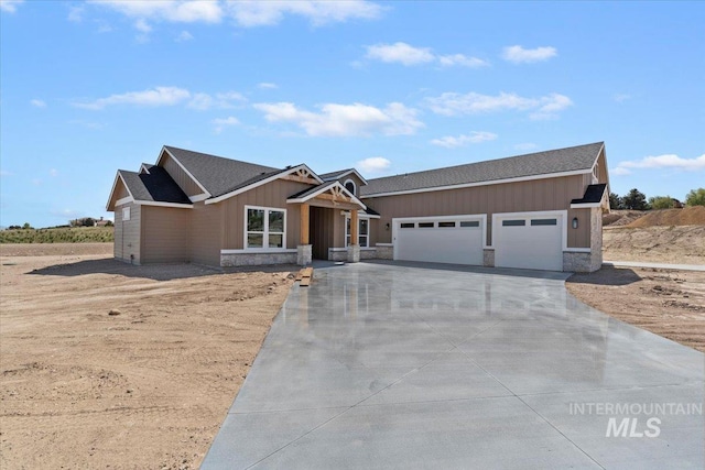 view of front facade with roof with shingles, an attached garage, stone siding, board and batten siding, and concrete driveway