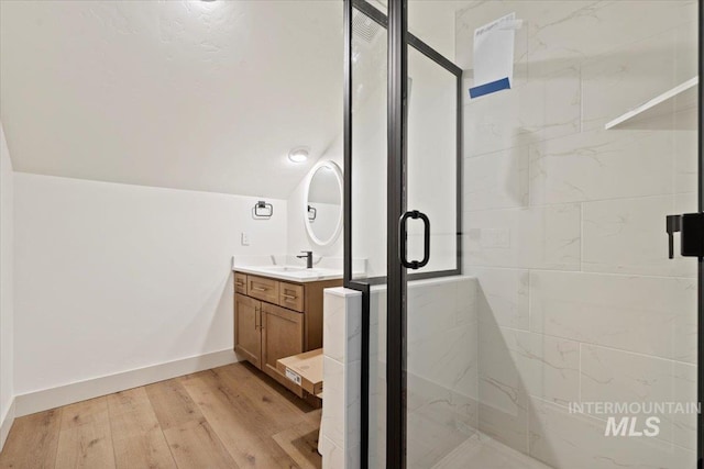 full bathroom with vanity, wood finished floors, lofted ceiling, baseboards, and a stall shower