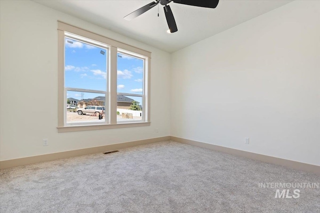 empty room featuring carpet floors, ceiling fan, baseboards, and visible vents