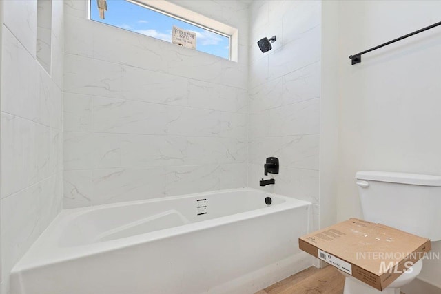 bathroom with toilet, shower / tub combination, and wood finished floors