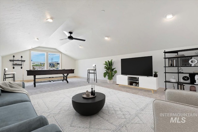 living area featuring carpet flooring, a ceiling fan, baseboards, and lofted ceiling