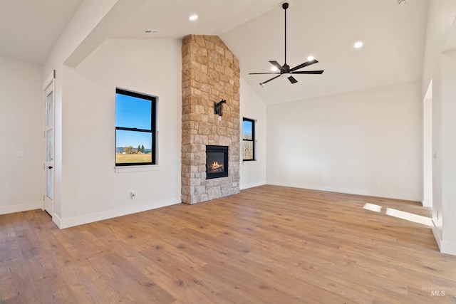 unfurnished living room featuring a ceiling fan, a fireplace, light wood finished floors, and high vaulted ceiling