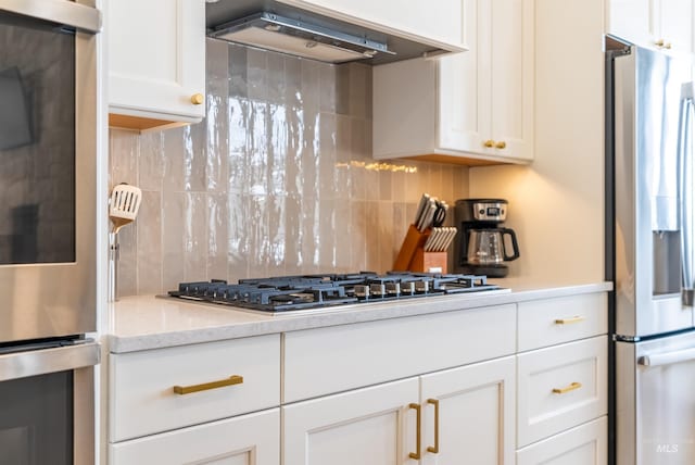 kitchen with decorative backsplash, white cabinetry, stainless steel appliances, and extractor fan