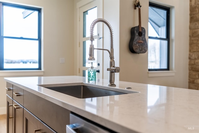 kitchen with light stone counters, dishwasher, and a sink
