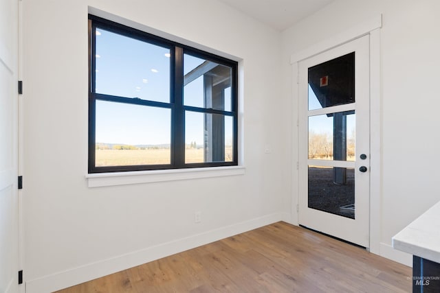 doorway to outside with baseboards and light wood-type flooring