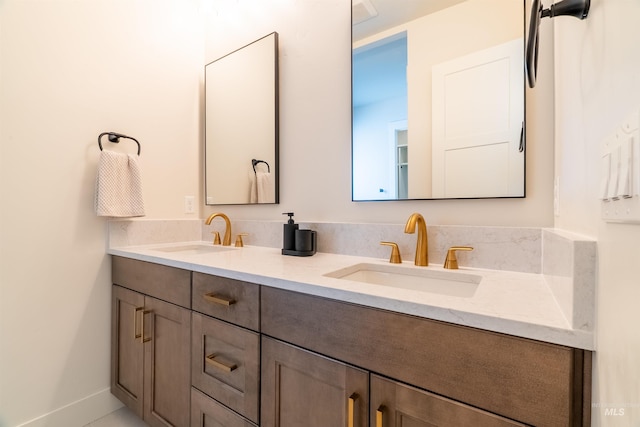 full bathroom with a sink, baseboards, and double vanity