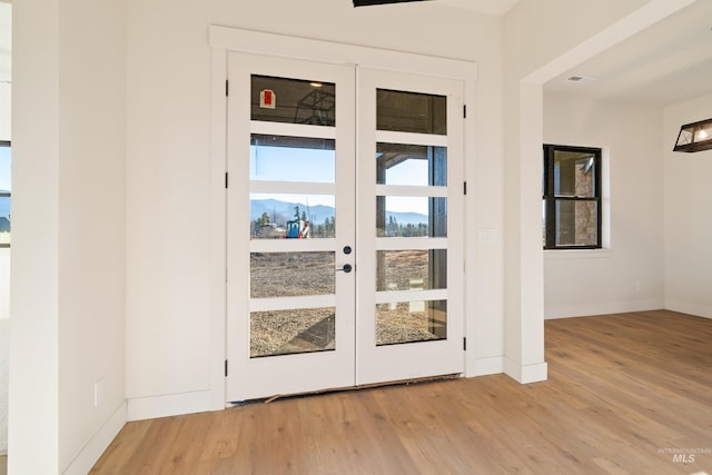 doorway to outside featuring french doors, light wood-type flooring, and baseboards