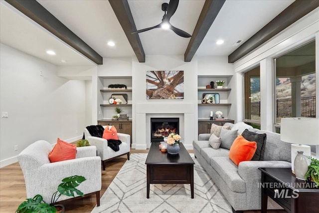 living room with light wood-type flooring, built in features, and ceiling fan