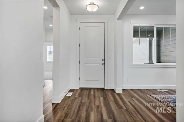 entrance foyer with baseboards, visible vents, and dark wood finished floors