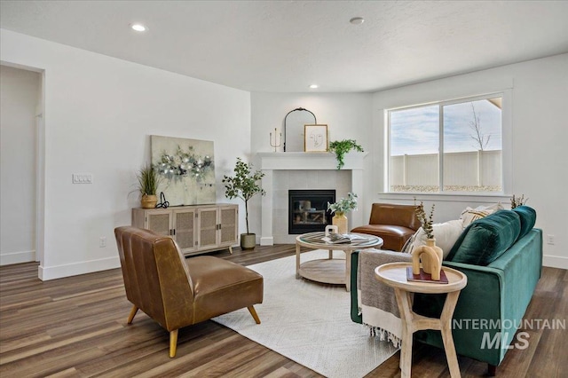living area with recessed lighting, a tiled fireplace, baseboards, and wood finished floors