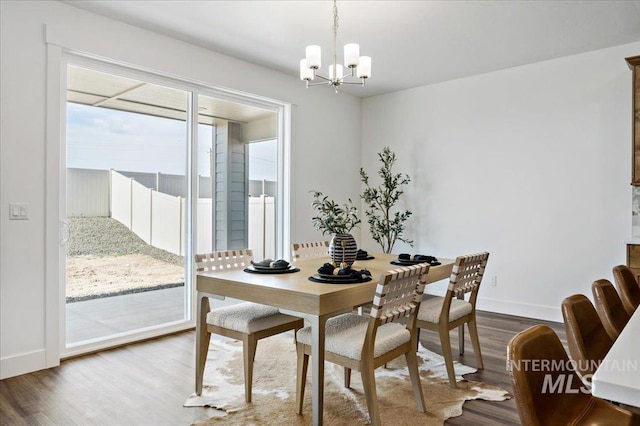 dining room featuring wood finished floors, a notable chandelier, and baseboards