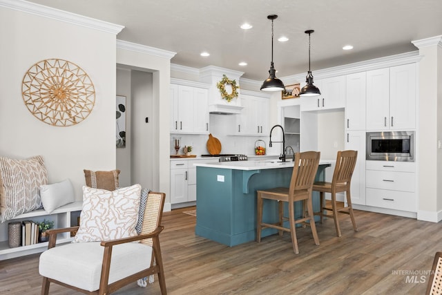 kitchen with stainless steel microwave, wood finished floors, white cabinets, and tasteful backsplash