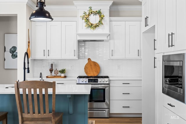 kitchen featuring light countertops, appliances with stainless steel finishes, ornamental molding, and backsplash