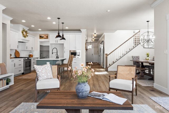 living area with recessed lighting, ornamental molding, wood finished floors, and stairway