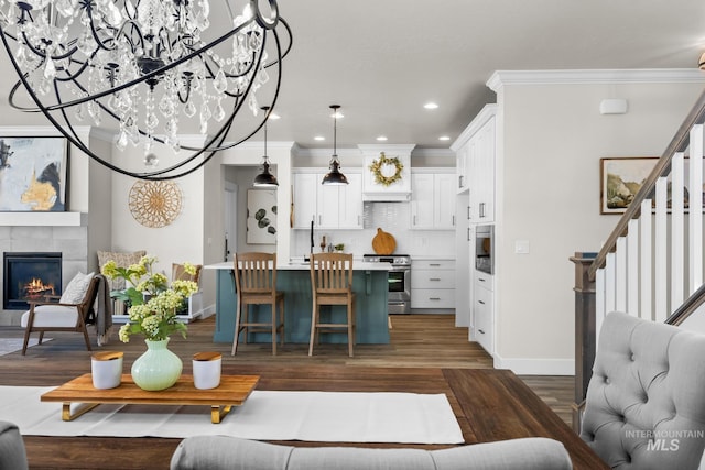 living area with recessed lighting, baseboards, wood finished floors, ornamental molding, and stairway