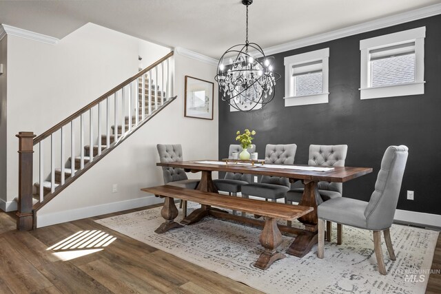 dining area with ornamental molding, wood finished floors, baseboards, stairway, and a notable chandelier