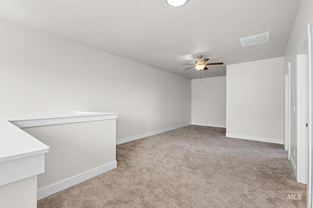 unfurnished room with visible vents, carpet, ceiling fan, and baseboards