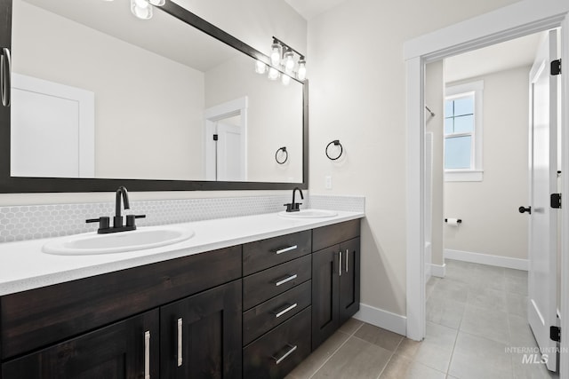bathroom featuring double vanity, a sink, baseboards, and tile patterned floors