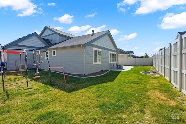 back of house featuring a yard, a fenced backyard, roof with shingles, and central air condition unit