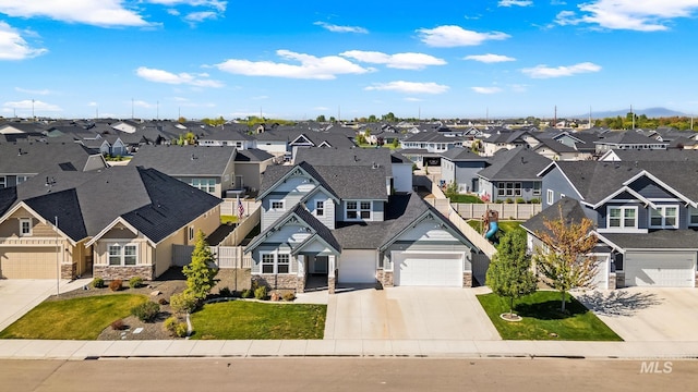 view of front of house featuring concrete driveway, an attached garage, a residential view, and stone siding