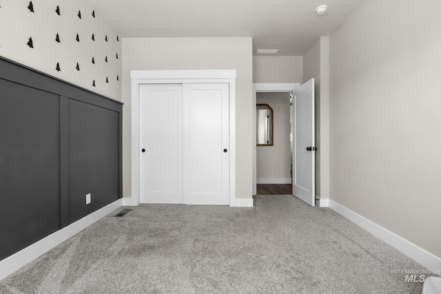 unfurnished bedroom with carpet floors, baseboards, a closet, and visible vents