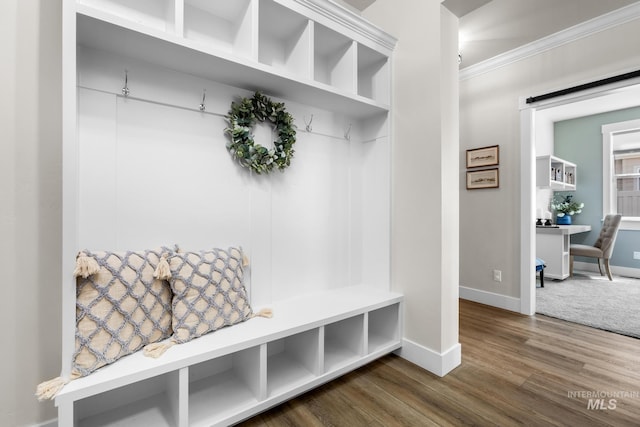 mudroom featuring baseboards, ornamental molding, dark wood-style floors, and a barn door